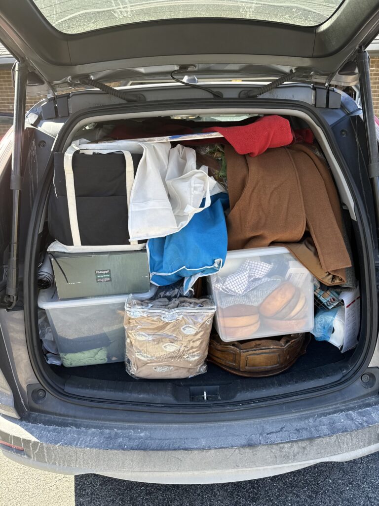 An SUV filled to the top with furniture, clothing, and home goods